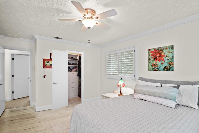 2414 SW Love Ct, Palm City, FL 34990 - bedroom with light wood-type flooring, ornamental molding, a walk in closet, a textured ceiling, and a closet