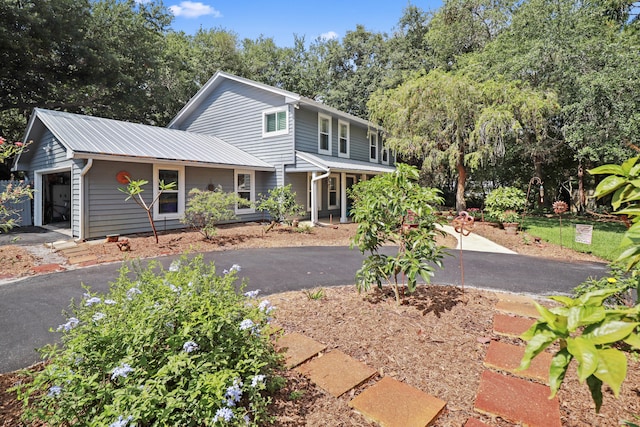 2414 SW Love Ct, Palm City, FL 34990 - traditional-style house featuring driveway, an attached garage, metal roof, and view of scattered trees
