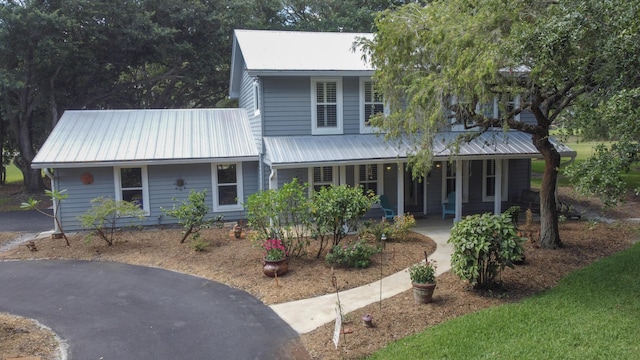 2414 SW Love Ct, Palm City, FL 34990 - view of front of house with metal roof, a porch, and asphalt driveway