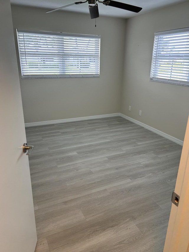 spare room with a ceiling fan, wood finished floors, and baseboards