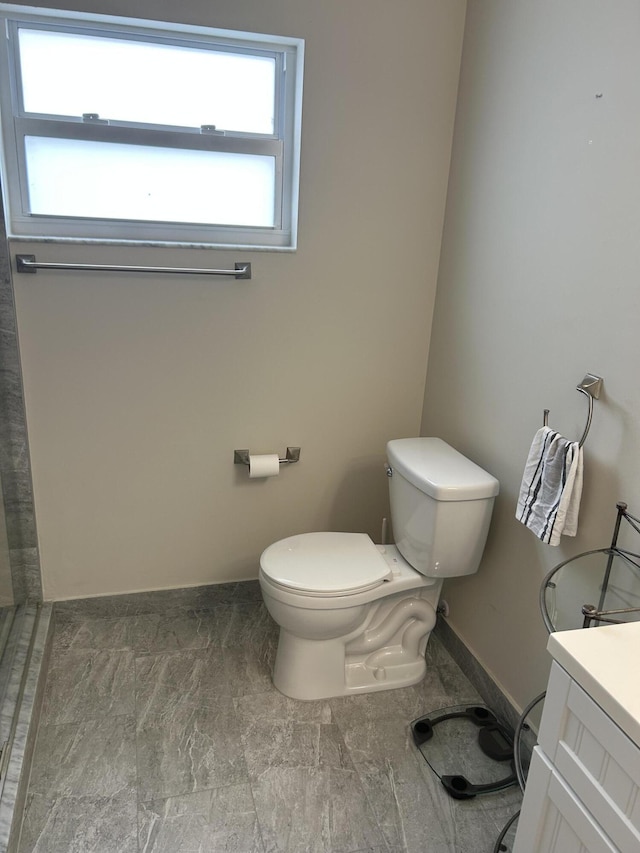 bathroom featuring toilet, baseboards, and vanity