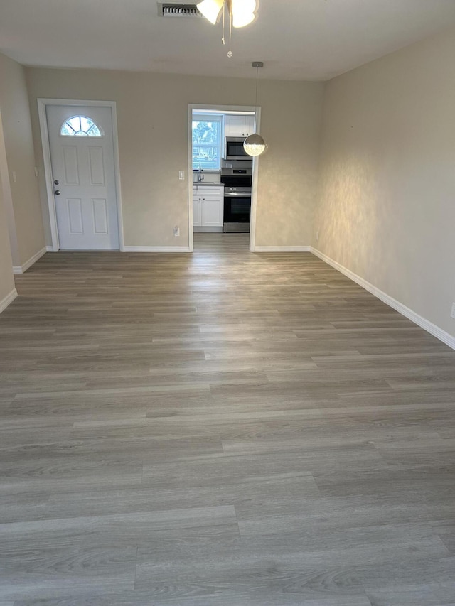 foyer with baseboards, ceiling fan, and light wood-style floors