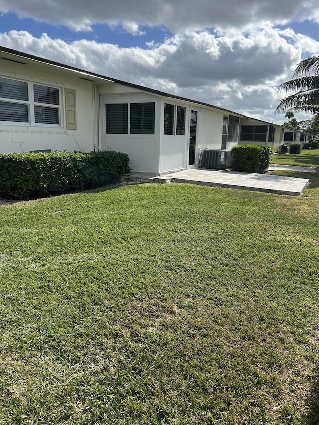 view of front of house with a front yard, central AC, and stucco siding