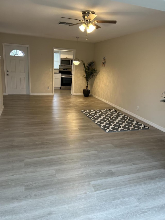 unfurnished living room with baseboards, ceiling fan, and wood finished floors