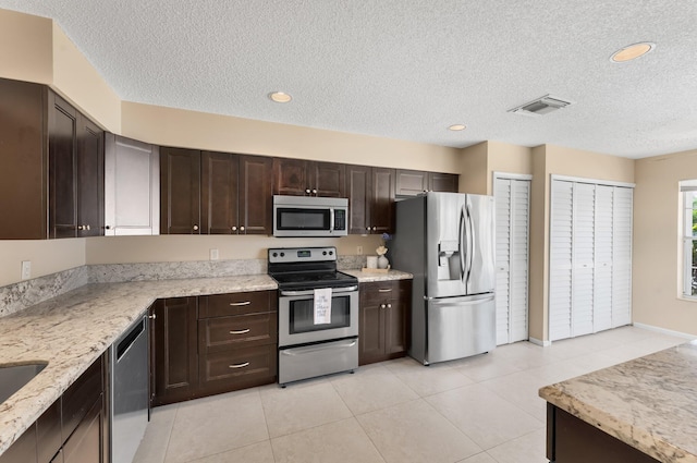 6616 Marissa Cir, Lake Worth, FL 33467 - kitchen featuring stainless steel appliances, a textured ceiling, dark brown cabinetry, light stone counters, and light tile patterned floors