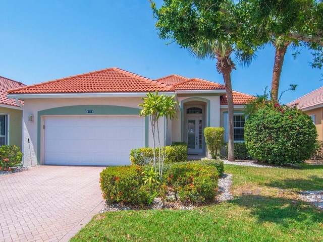 mediterranean / spanish house featuring a garage, stucco siding, a tiled roof, and driveway