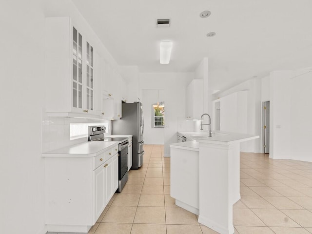 kitchen featuring stainless steel range with electric stovetop, a sink, light tile patterned floors, light countertops, and white cabinets