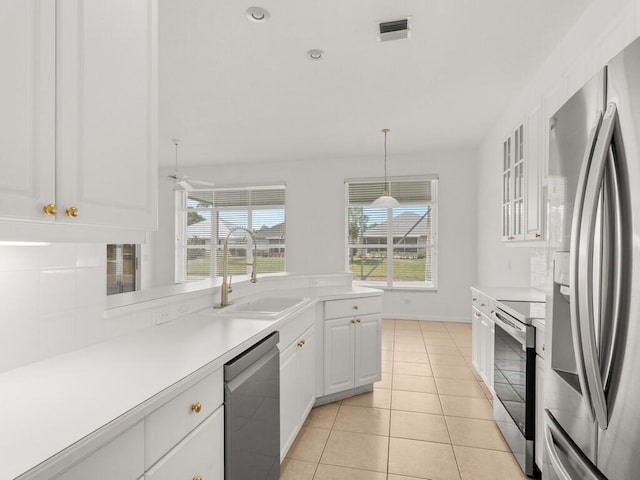 kitchen with appliances with stainless steel finishes, white cabinets, a sink, light countertops, and light tile patterned flooring