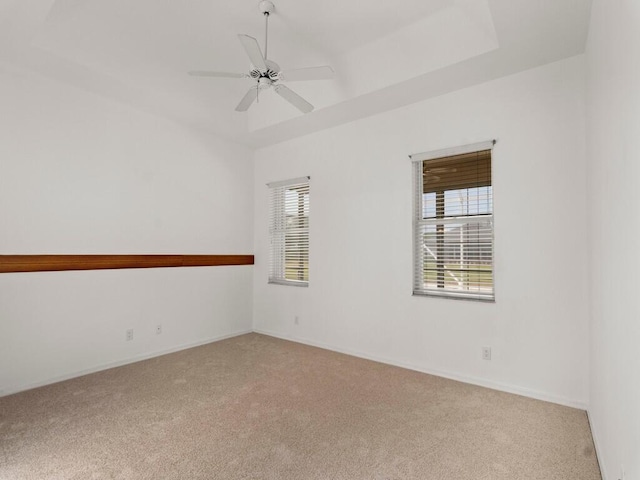 carpeted spare room with a ceiling fan and baseboards