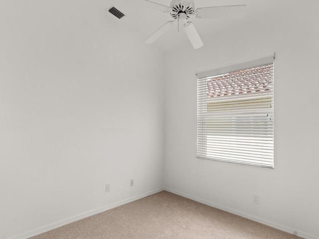 spare room with light colored carpet, baseboards, and a ceiling fan
