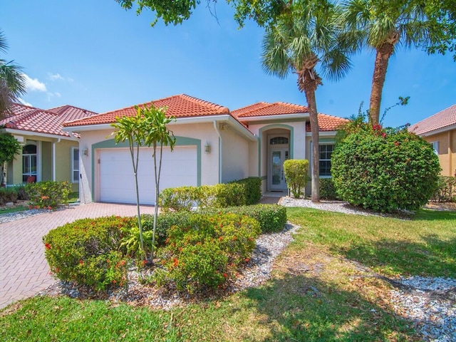 mediterranean / spanish home featuring an attached garage, a tile roof, stucco siding, and driveway