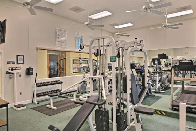 gym with ceiling fan, a high ceiling, and carpet