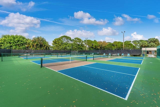view of tennis court with fence and view of scattered trees
