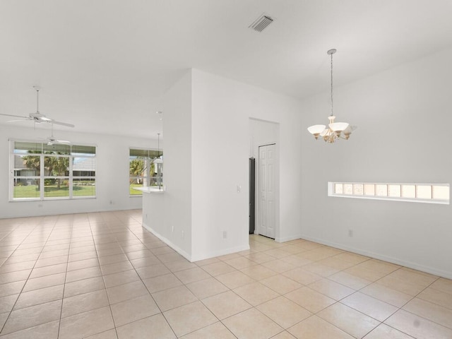 empty room featuring a chandelier, a ceiling fan, light tile patterned flooring, and baseboards