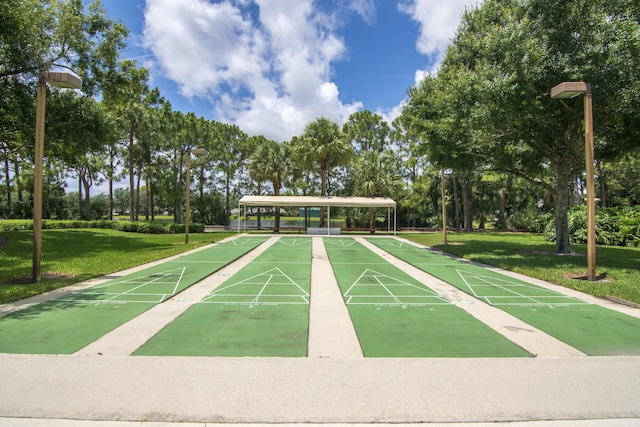 view of community featuring a yard, shuffleboard, and view of wooded area