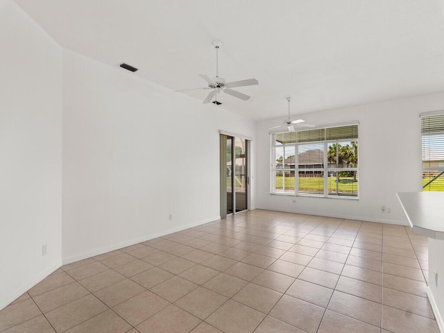 empty room featuring light tile patterned floors, a ceiling fan, and baseboards