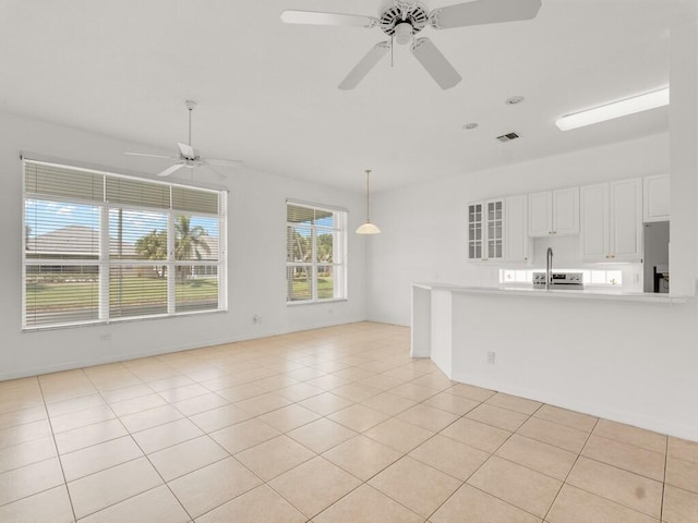 unfurnished living room with a ceiling fan, light tile patterned floors, and baseboards