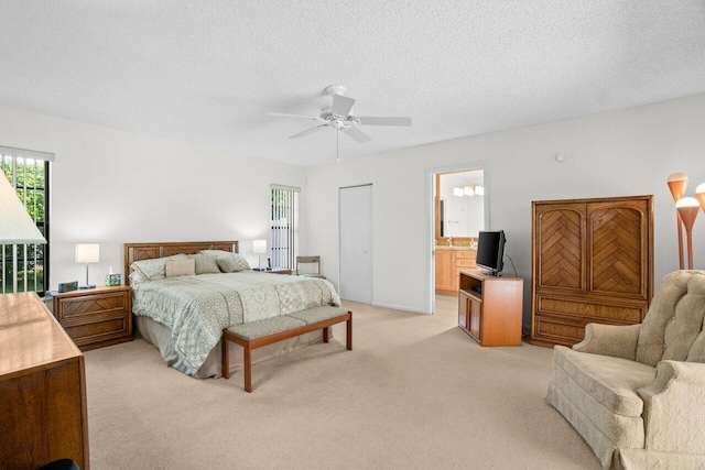 bedroom with multiple windows, light carpet, a textured ceiling, ceiling fan, and connected bathroom