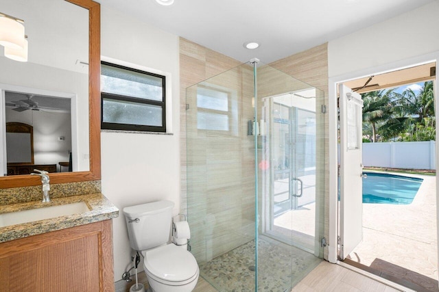full bathroom featuring a stall shower, toilet, vanity, a ceiling fan, and recessed lighting