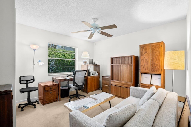 home office featuring light colored carpet, a ceiling fan, a textured ceiling, and baseboards