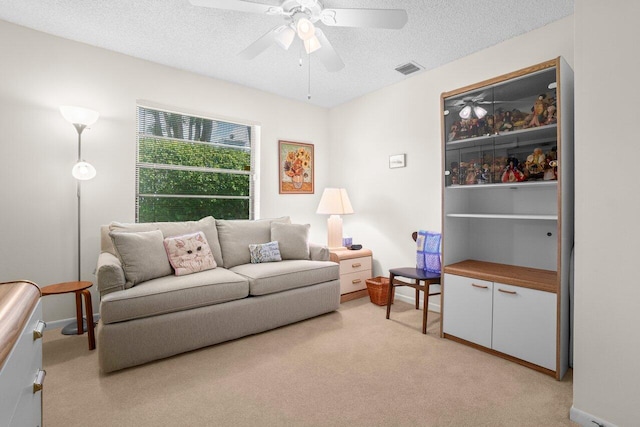living area with light carpet, ceiling fan, a textured ceiling, and baseboards