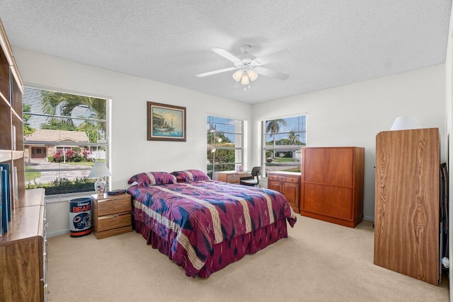 bedroom featuring light colored carpet, a textured ceiling, and ceiling fan
