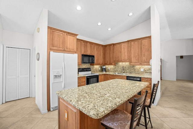 kitchen with black appliances, a sink, a center island, light tile patterned floors, and vaulted ceiling