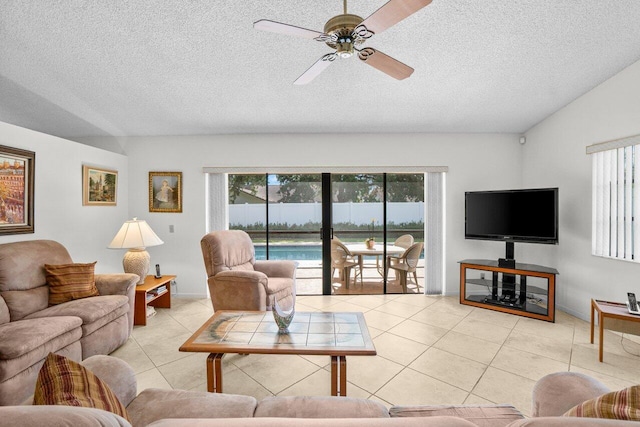 living room with tile patterned floors, a ceiling fan, a textured ceiling, and baseboards