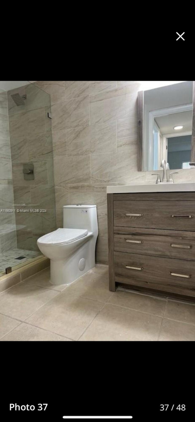 307 Pine Ridge Cir Unit C1, Greenacres, FL 33463 - bathroom with tile patterned flooring, vanity, a tile shower, toilet, and tile walls