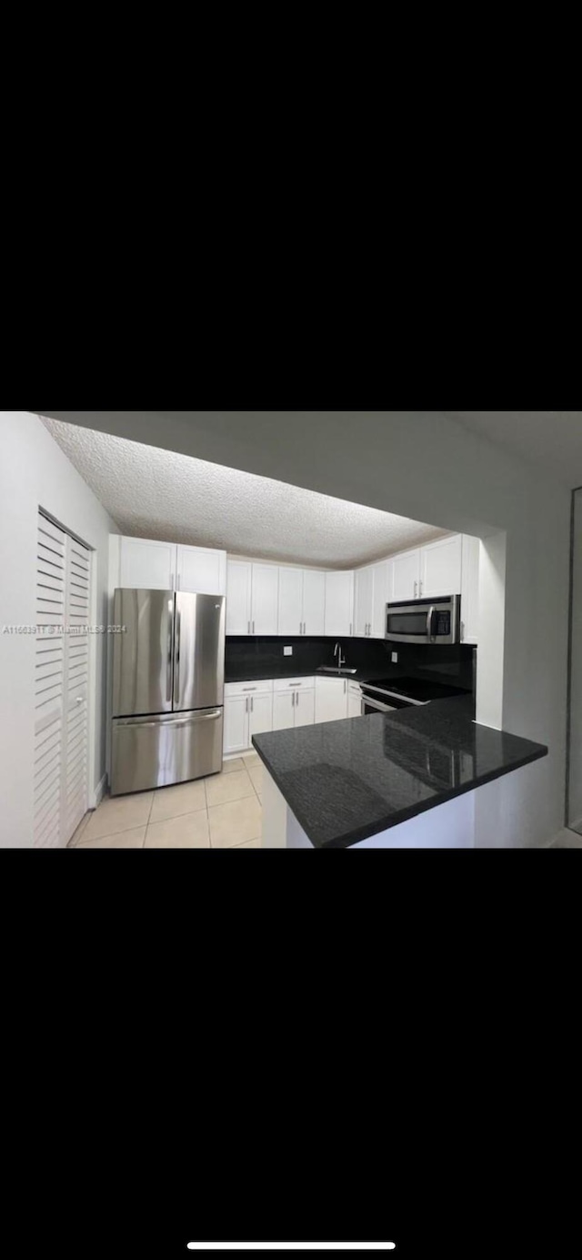 307 Pine Ridge Cir Unit C1, Greenacres, FL 33463 - kitchen featuring stainless steel appliances, a peninsula, light tile patterned floors, white cabinets, and a sink