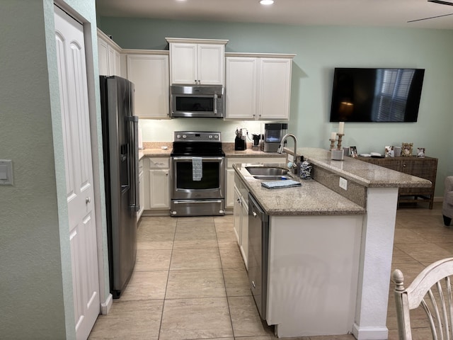 275 SW 7th Ct, Pompano Beach, FL 33060 - kitchen with stainless steel appliances, a sink, light tile patterned floors, white cabinetry, and light stone counters