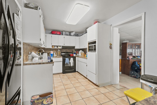 933 S Ridge St, Lake Worth Beach, FL 33460 - kitchen featuring black appliances, light tile patterned floors, tasteful backsplash, and white cabinets
