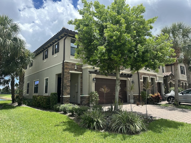 13007 Anthorne Ln, Boynton Beach, FL 33436 - view of front of house with stone siding, decorative driveway, a front lawn, stucco siding, and an attached garage