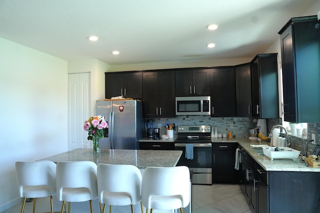 13007 Anthorne Ln, Boynton Beach, FL 33436 - kitchen featuring appliances with stainless steel finishes, tasteful backsplash, a sink, light stone countertops, and recessed lighting