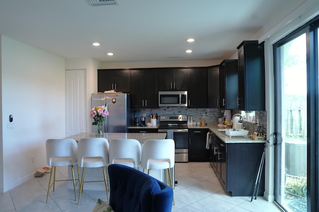 13007 Anthorne Ln, Boynton Beach, FL 33436 - kitchen featuring appliances with stainless steel finishes, backsplash, a sink, dark cabinets, and a kitchen island