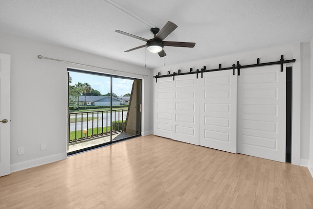 1402 Nebraska Ave Unit 3B, Fort Pierce, FL 34950 - unfurnished bedroom featuring a barn door, access to outside, light wood-style floors, a textured ceiling, and baseboards