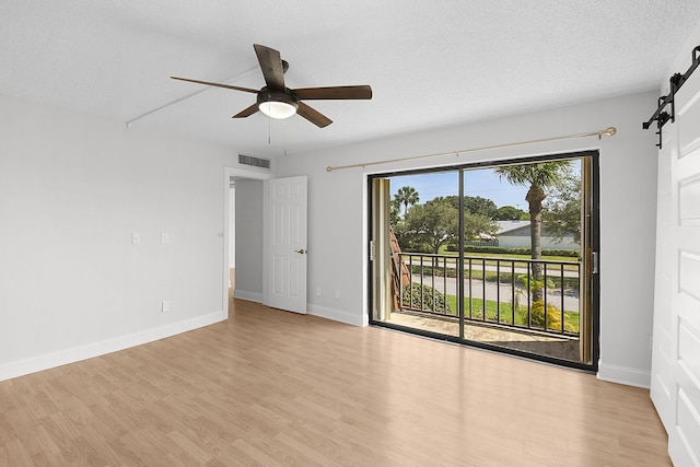 1402 Nebraska Ave Unit 3B, Fort Pierce, FL 34950 - empty room featuring a barn door, wood finished floors, a ceiling fan, baseboards, and a textured ceiling