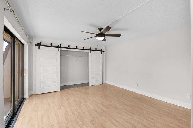 1402 Nebraska Ave Unit 3B, Fort Pierce, FL 34950 - unfurnished bedroom with a barn door, light wood finished floors, a textured ceiling, a closet, and baseboards