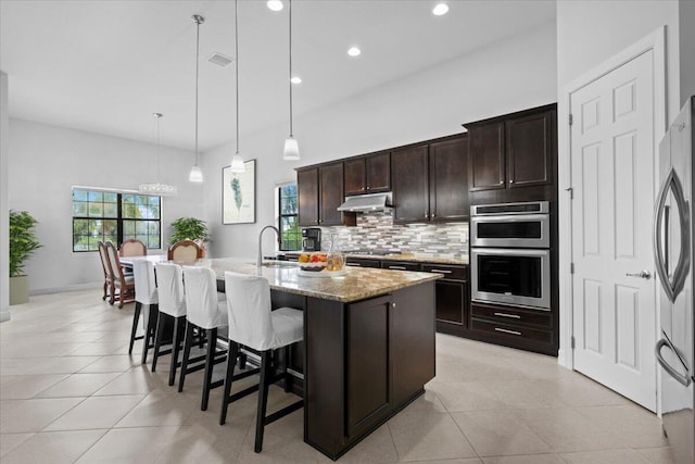 10557 Pisa Rd, Wellington, FL 33414 - kitchen featuring backsplash, appliances with stainless steel finishes, a kitchen bar, light stone countertops, and pendant lighting
