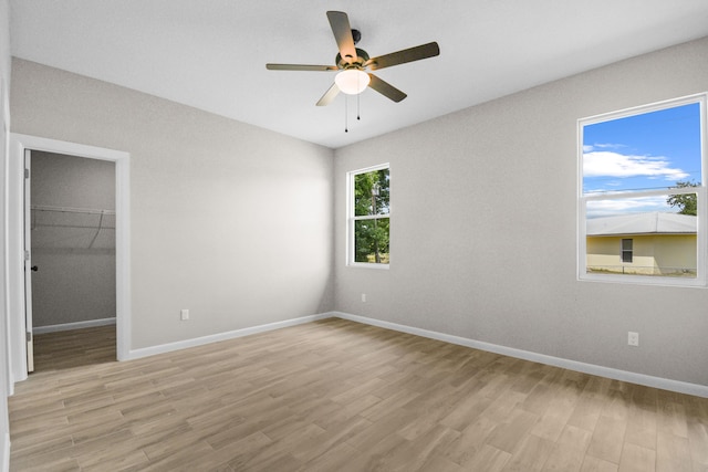 3269 NW 24th Ave, Okeechobee, FL 34972 - unfurnished bedroom featuring light wood finished floors, a walk in closet, baseboards, and a ceiling fan