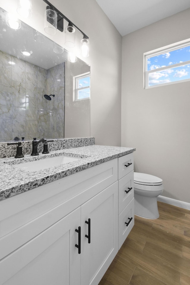 3269 NW 24th Ave, Okeechobee, FL 34972 - bathroom with tiled shower, toilet, vanity, wood finished floors, and baseboards