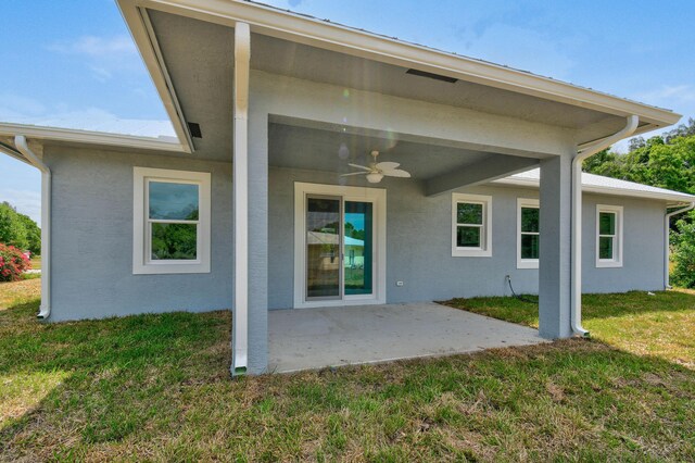 3269 NW 24th Ave, Okeechobee, FL 34972 - back of house featuring a ceiling fan, a patio area, a lawn, and stucco siding