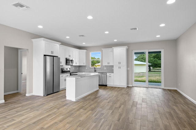 3269 NW 24th Ave, Okeechobee, FL 34972 - kitchen with stainless steel appliances, white cabinetry, decorative backsplash, light wood-style floors, and recessed lighting