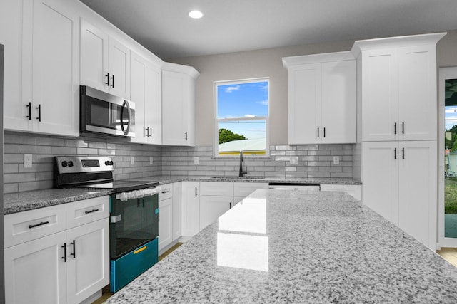 3269 NW 24th Ave, Okeechobee, FL 34972 - kitchen featuring stainless steel appliances, a sink, white cabinets, decorative backsplash, and recessed lighting