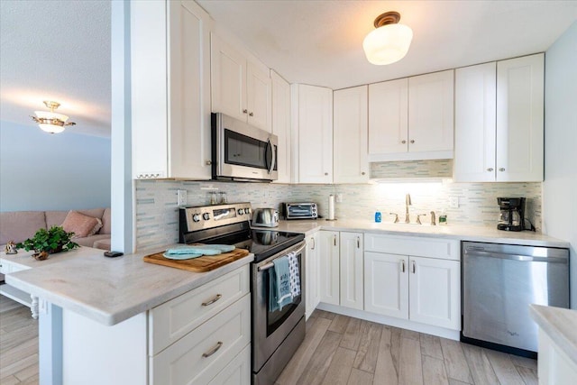 71 S Las Olas Dr, Jensen Beach, FL 34957 - kitchen with stainless steel appliances, a sink, white cabinetry, and tasteful backsplash