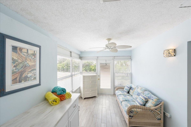 71 S Las Olas Dr, Jensen Beach, FL 34957 - living area with healthy amount of natural light, a ceiling fan, a textured ceiling, and light wood-type flooring