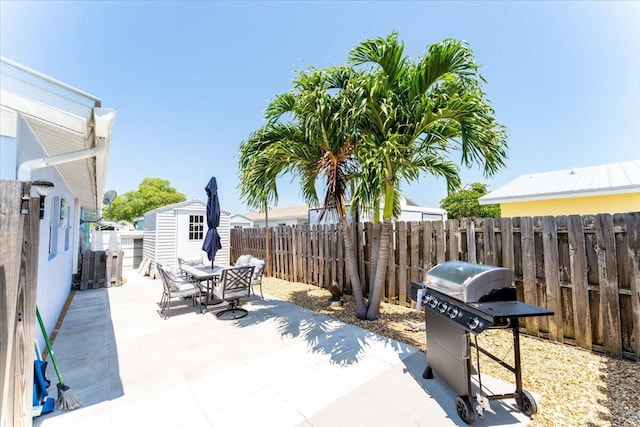 71 S Las Olas Dr, Jensen Beach, FL 34957 - view of patio with a storage unit, an outbuilding, outdoor dining area, grilling area, and a fenced backyard