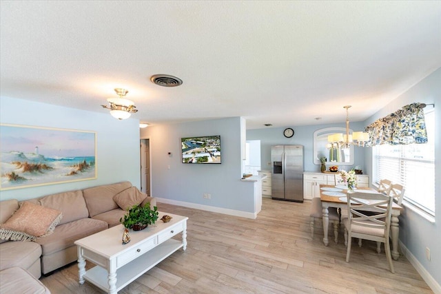 71 S Las Olas Dr, Jensen Beach, FL 34957 - living room featuring a chandelier, light wood-style flooring, and baseboards