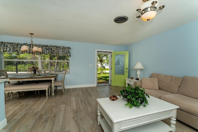 71 S Las Olas Dr, Jensen Beach, FL 34957 - living room with wood finished floors, a textured ceiling, a chandelier, and baseboards
