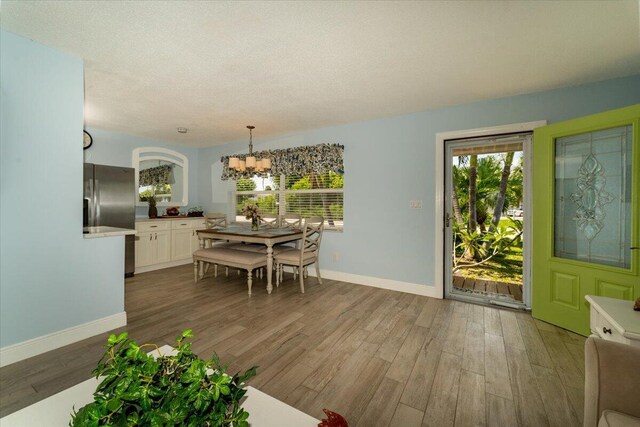 71 S Las Olas Dr, Jensen Beach, FL 34957 - dining room featuring a chandelier, wood finished floors, baseboards, and a textured ceiling